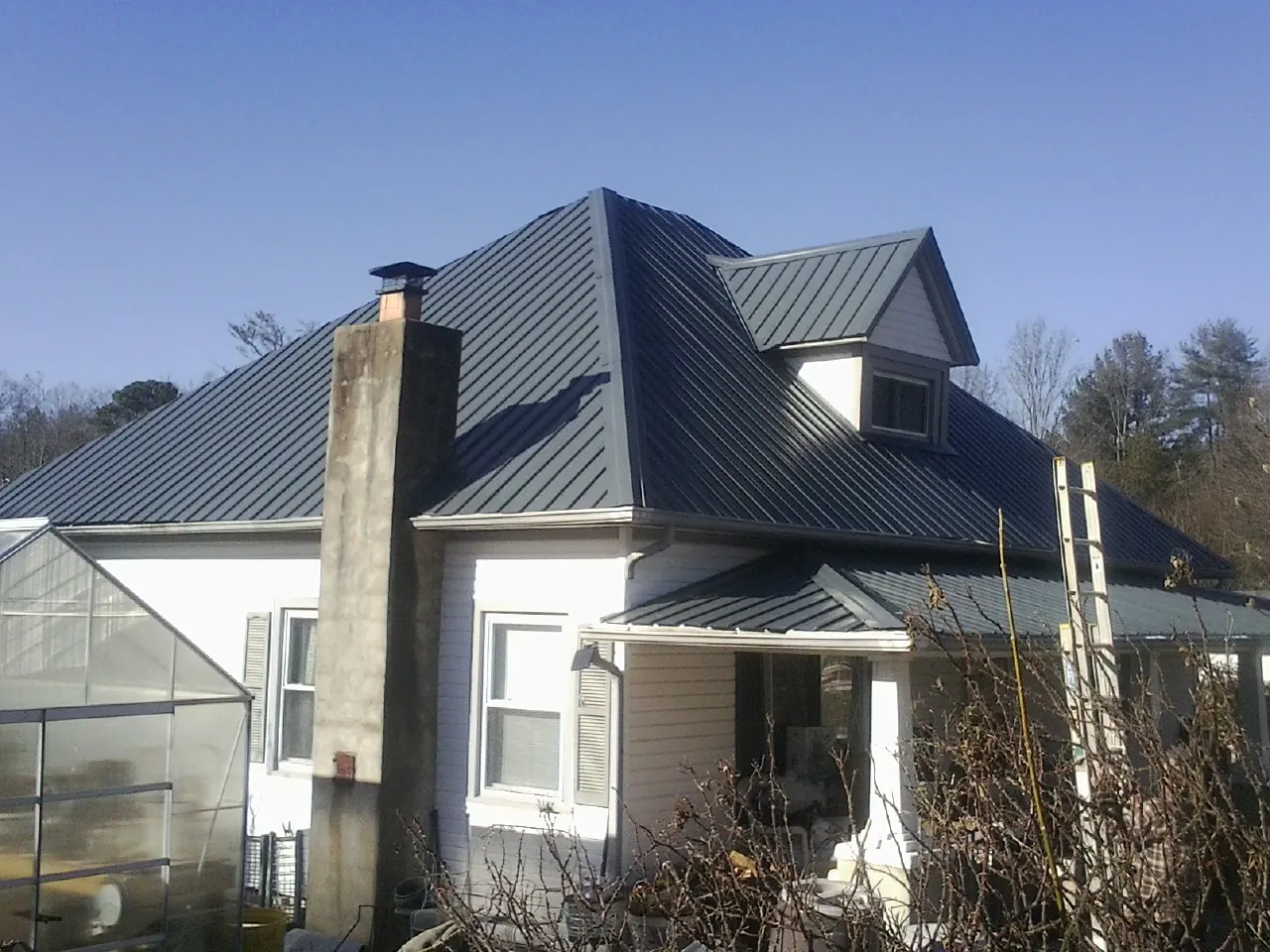 Dark blue standing seam metal roof on a white farmhouse with dormer — Slate & Tile Roof Repair by Roofing Brothers in Eden