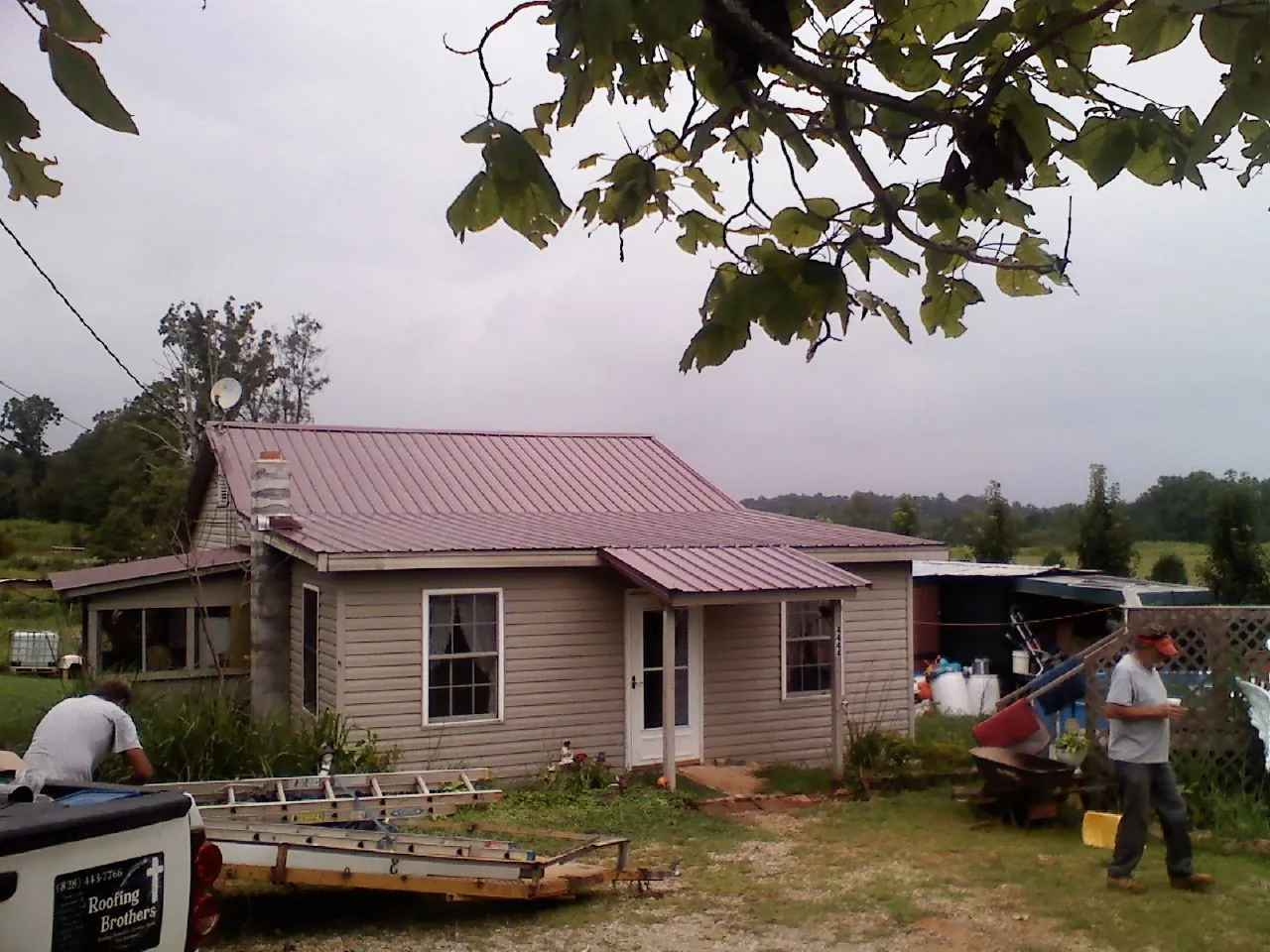 Crew finishing a mauve metal roof on a small farmhouse in Eden